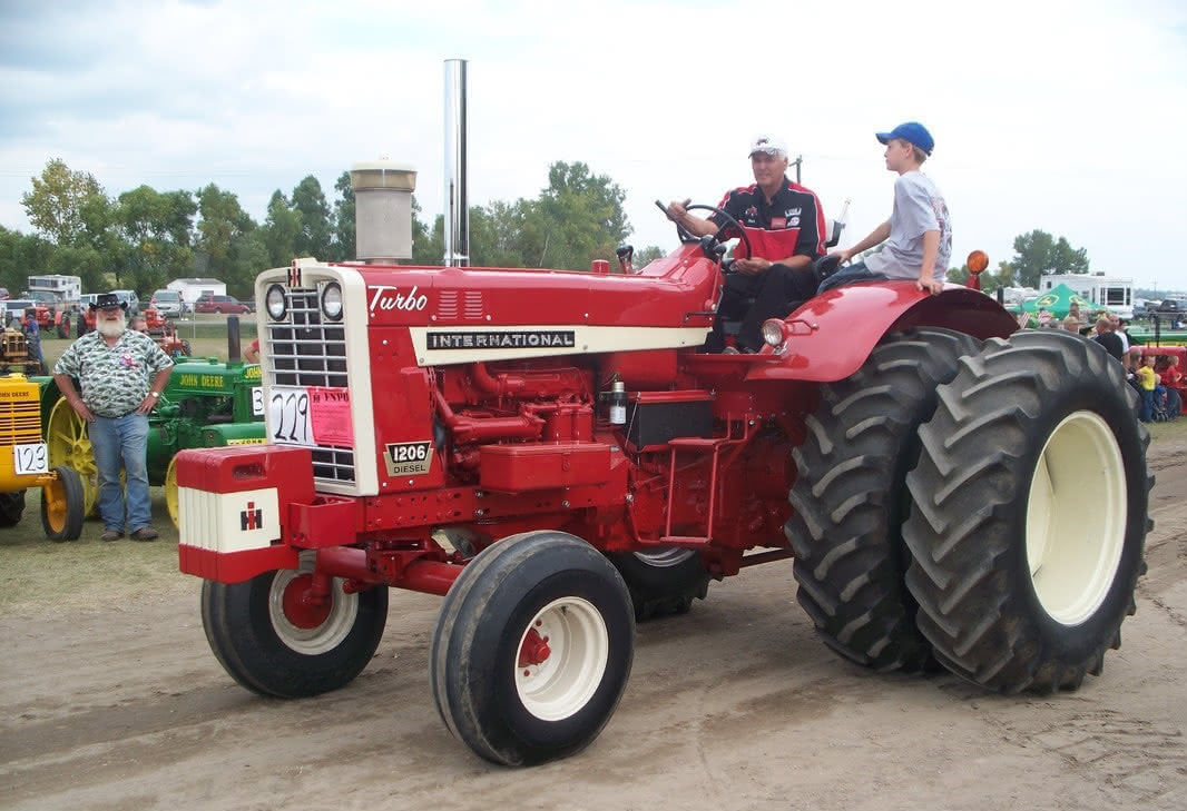 Two people riding on a red tractor